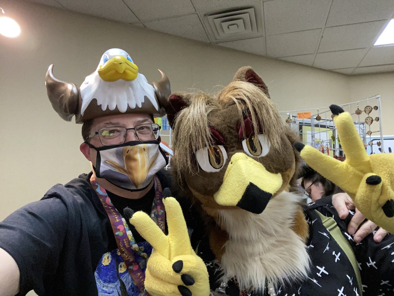 Me in a silly eagle hat posing with Horus the gryphon in fursuit.
